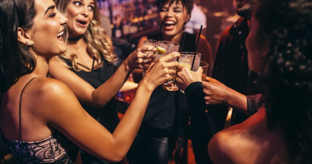 Group of friends partying in a nightclub and toasting drinks. Happy young people with cocktails at pub.