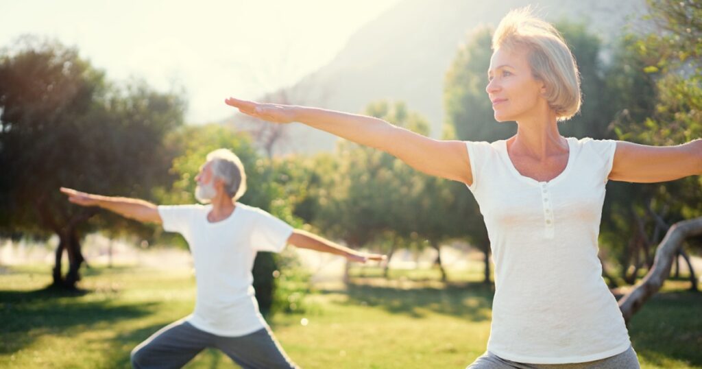 Yoga at park. Senior family couple exercising outdoors. Concept of healthy lifestyle.