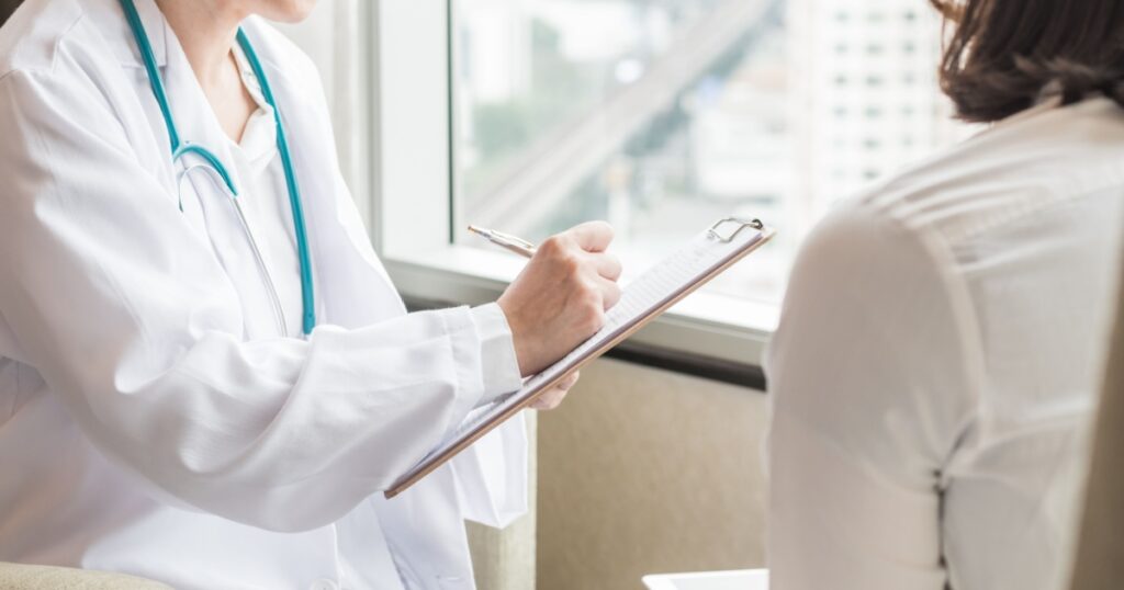 Doctor (gynecologist or psychiatrist) consulting and diagnostic examining woman patient's health in medical clinic or hospital healthcare service center