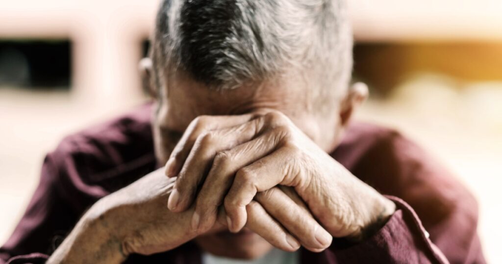 senior man covering his face with his hands.vintage tone