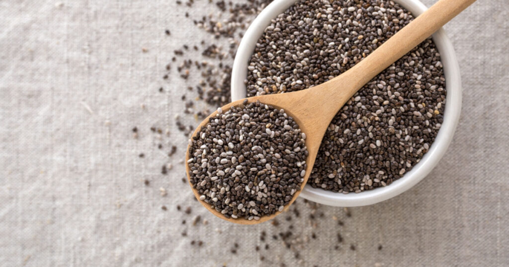 Chia seeds in wooden spoon and bowl from top view with space