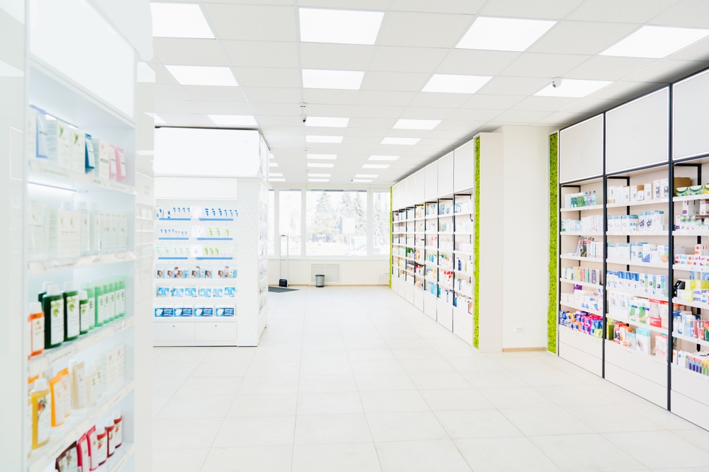 Spacious modern new white drugstore pharmacy chemist`s store with shelves full of medicines, pills, vitamins, painkillers, antibiotics without visitors
