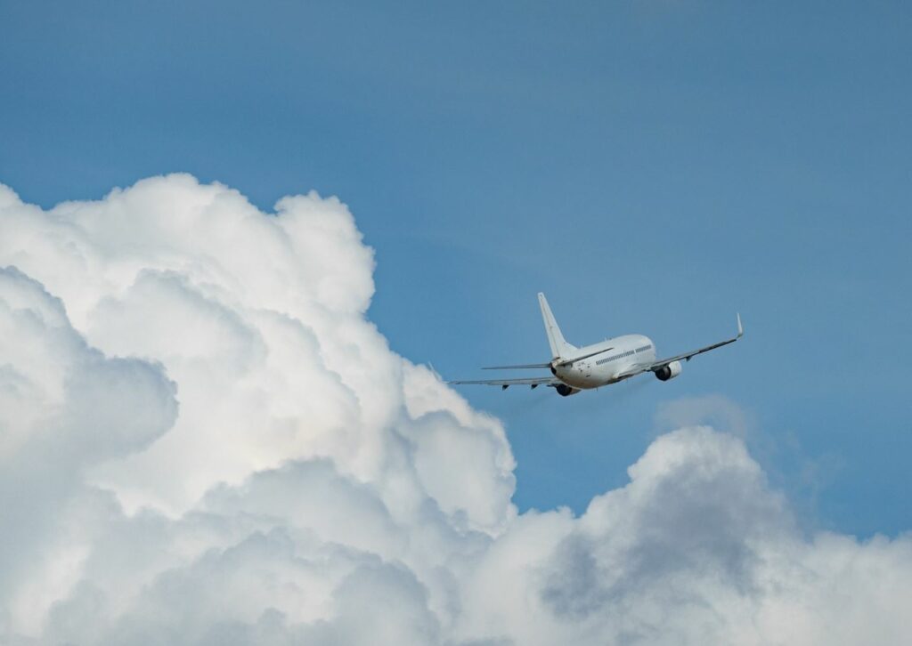 An airplane in the clouds with a blue sky in the background. 