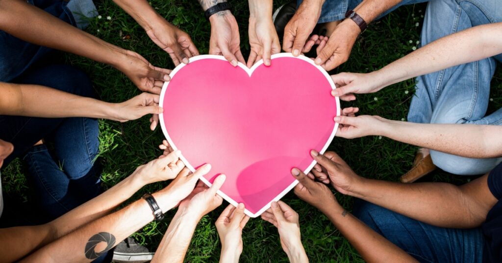 Group of people holding a pink heart icon