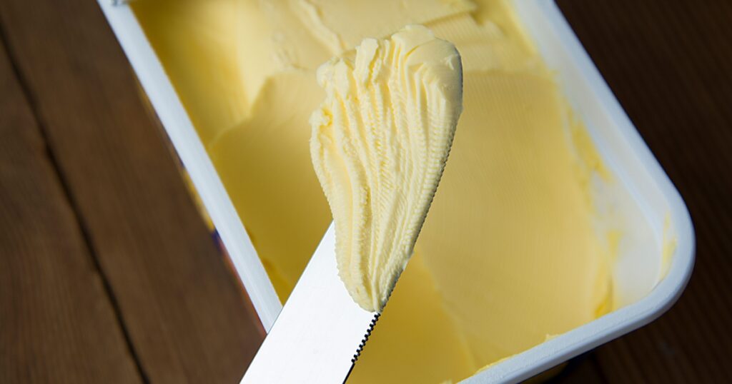 Whipped butter in plastic container with knife, butter for cooking and sandwiches.