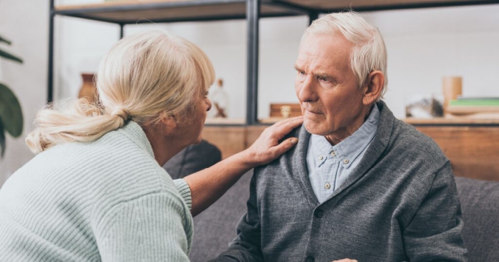 retired couple holding hands and looking at each other at home