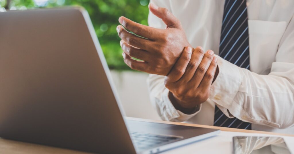 Businessman pain in hands while woking with laptop. Office syndrome concept.