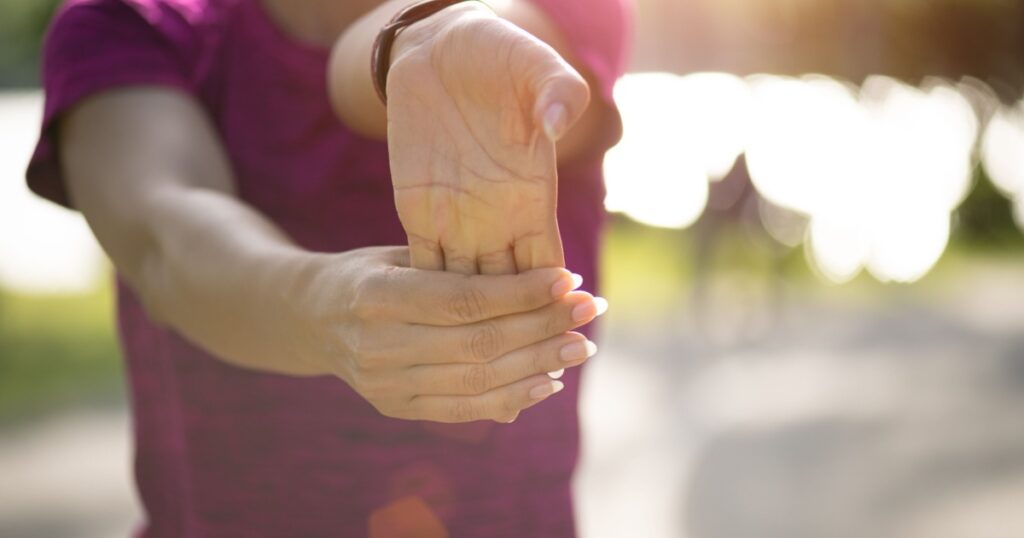Young fitness woman runner stretching hand before run in the park. Outdoor exercise activities concept.