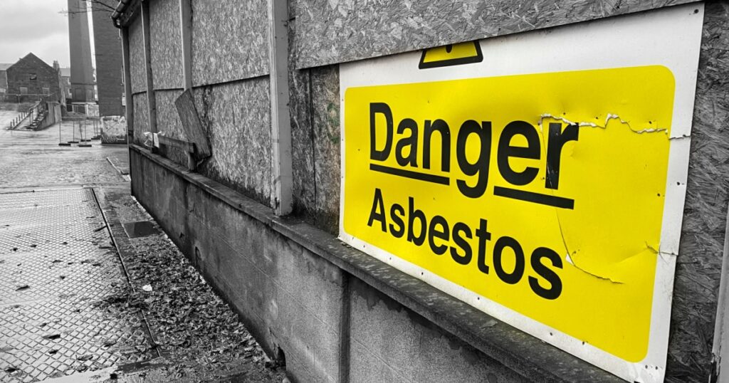 Asbestos danger sign at building construction site refurbishment of old building