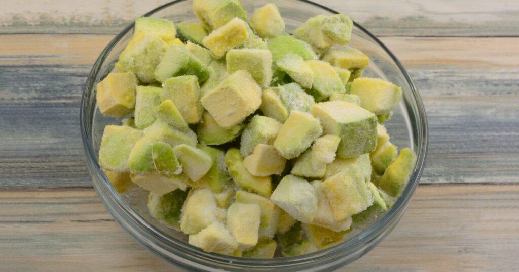 Frozen avocado chunks thawing in glass ingredient bowl on table