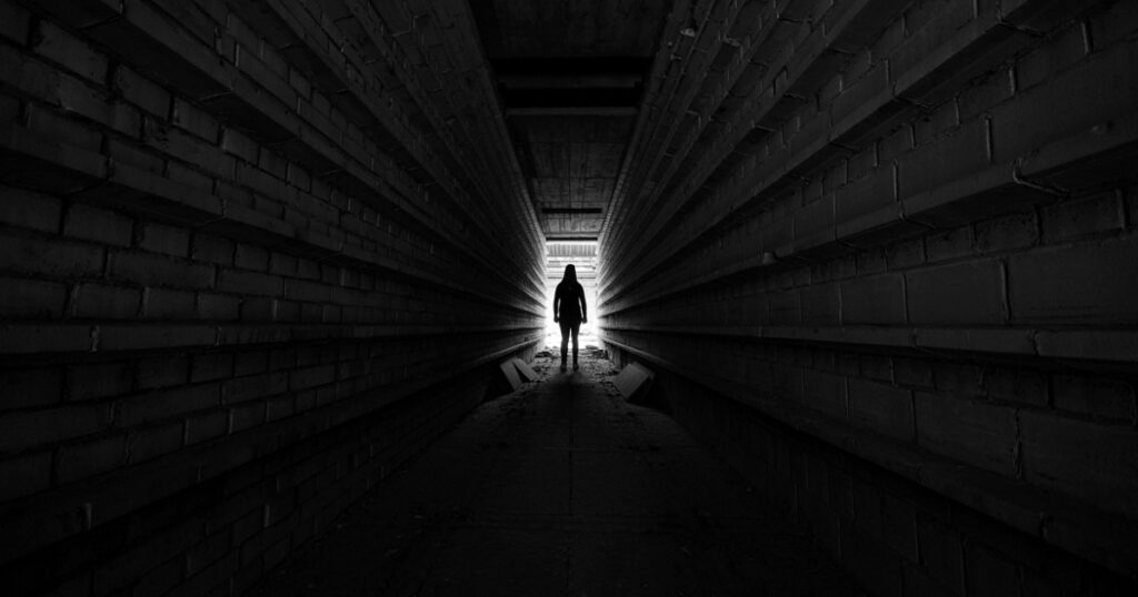 Person standing in light at the end of tunnel, silhouette