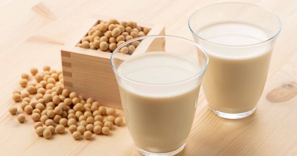 Soy milk in a glass on a wooden background. Soybeans in a masu in the background