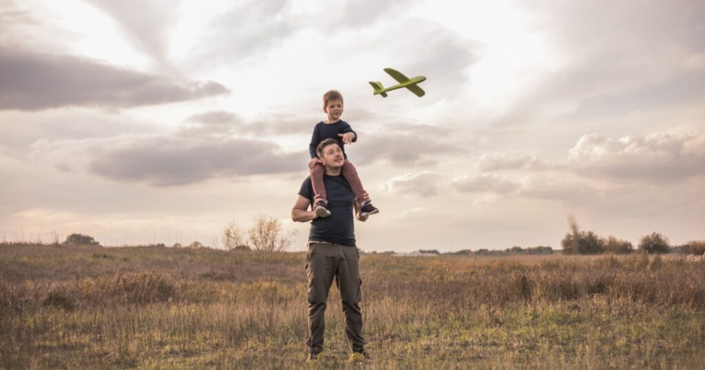 Father and son playing outside with plane toy. Childhood memories