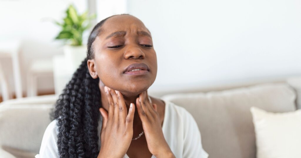 Close up of young woman rubbing her inflamed tonsils, tonsilitis problem, cropped. Woman with thyroid gland problem, touching her neck, girl has a sore throat