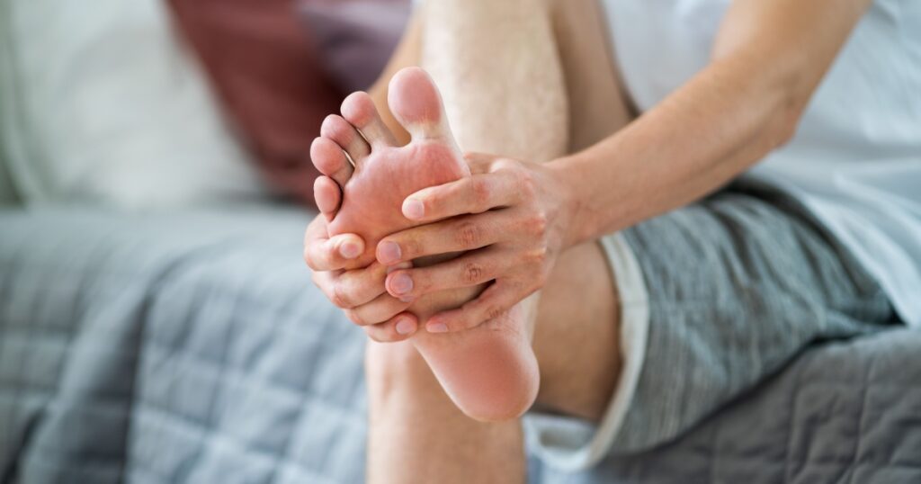 Foot pain, man suffering from feet ache in home interior, podiatry concept
