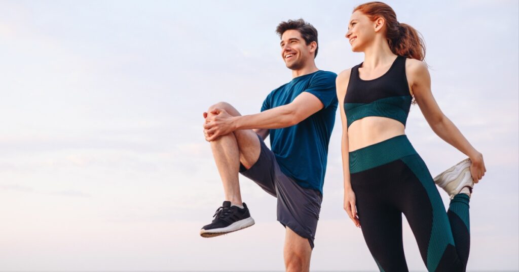 Lower couple young two friend strong sporty sportswoman sportsman woman man in sport clothes warm up training do stretch exercise on sand sea ocean beach outdoor jog on seaside in summer day morning