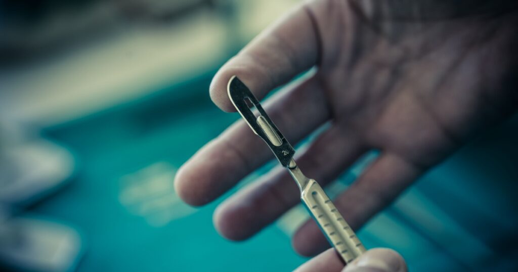 the hands of a surgeon using a metal scalpel
