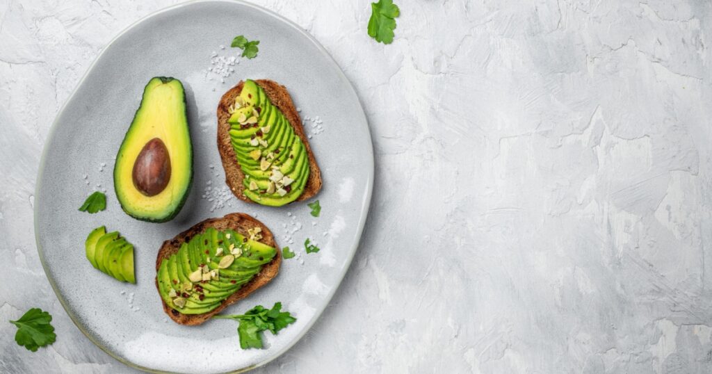 Healthy avocado toasts for breakfast or lunch with rye bread, sliced avocado, pumpkin seeds, salt and pepper. Vegetarian food. Plant-based diet. Clean eating. Top view. Copy space,