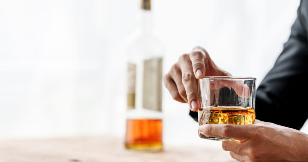 Sad depressed addicted drunk guy, Alone asian man drinker alcoholic sitting at bar counter with glass drinking whiskey.