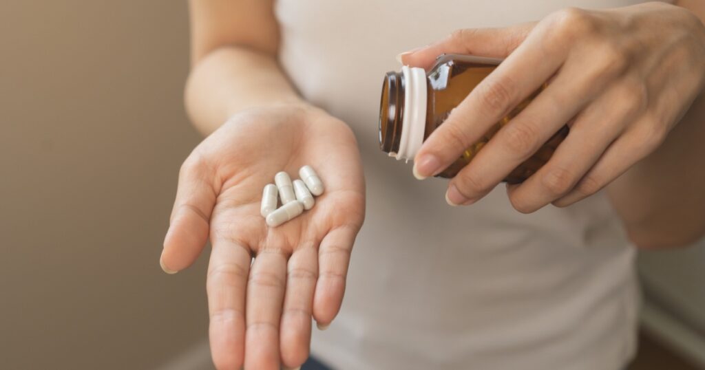Dietary supplement or sick, asian young woman, girl hold pills, drugs medical tablet on hand pouring capsules from medication bottle, take vitamin for treatment for skin, hair at home, healthcare.