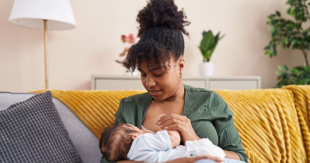 Mother and son sitting on sofa breastfeeding at home