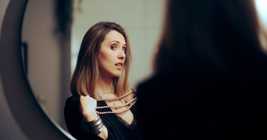 Vain Rich Woman Trying on Jewelry in the Mirror. Shallow narcissistic lady loving material possessions