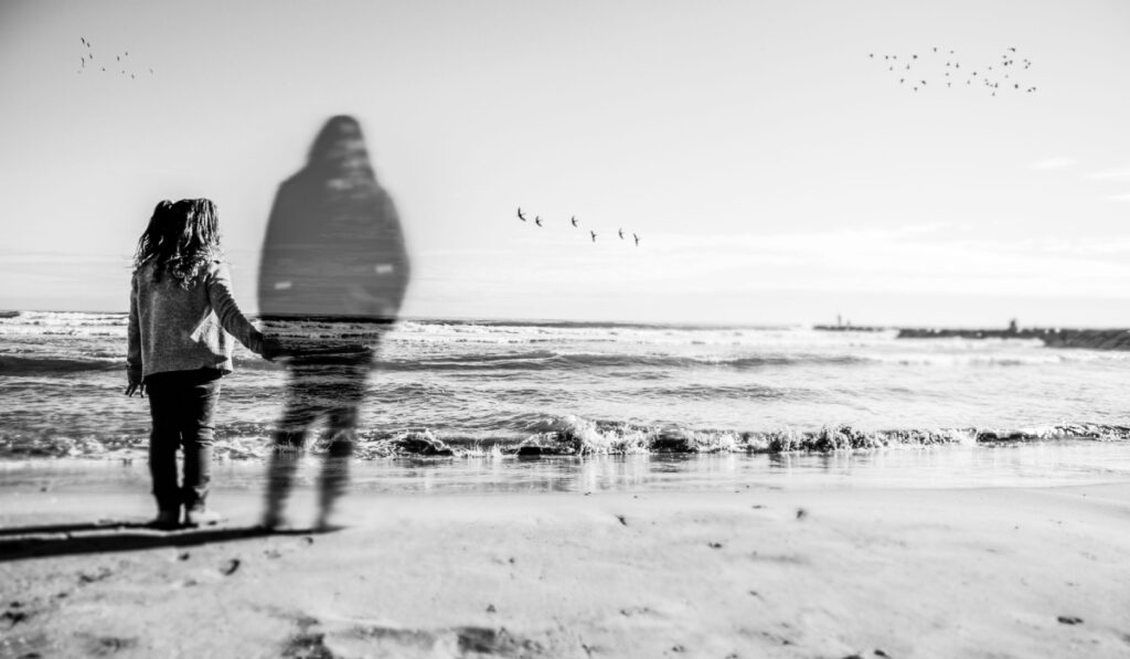 A girl holds the hand what appears to be the spirit of his dead mother. The image has been selectively blurred to give a touch of mystery. Can see some birds in the horizon