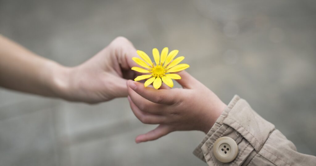 Parent and child hands handing yellow flowers