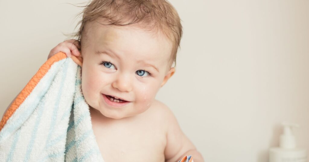 Baby after bathing, with towel and lotion