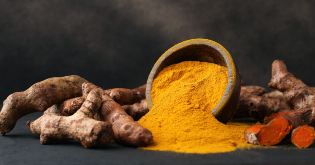 Turmeric powder and fresh turmeric on wooden background.with copy space.
