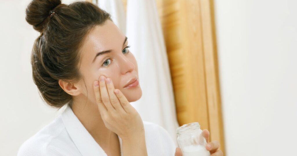 Woman is moisturizing her skin with a coconut oil