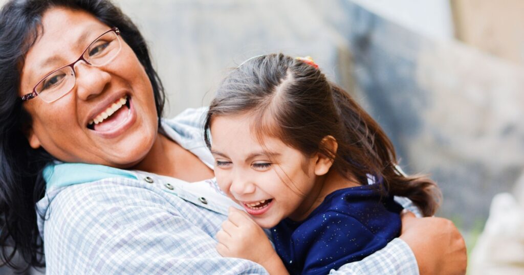 Happy latin mom and little daughter outside.
