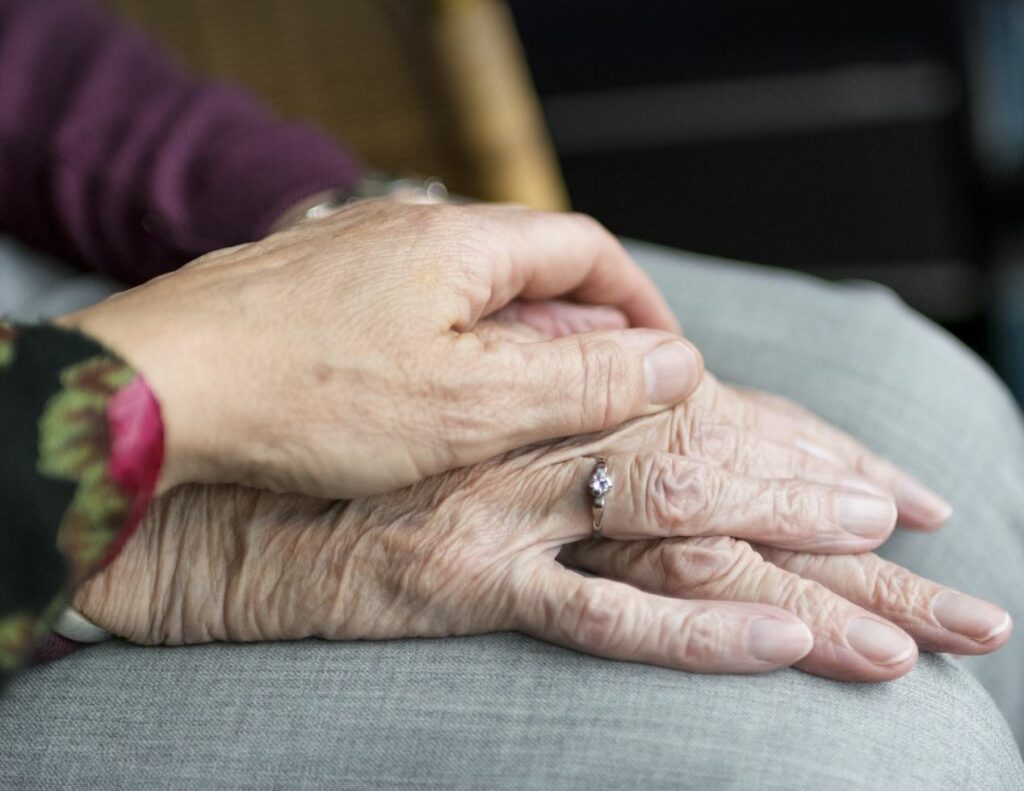 Elderly couple holds hands.