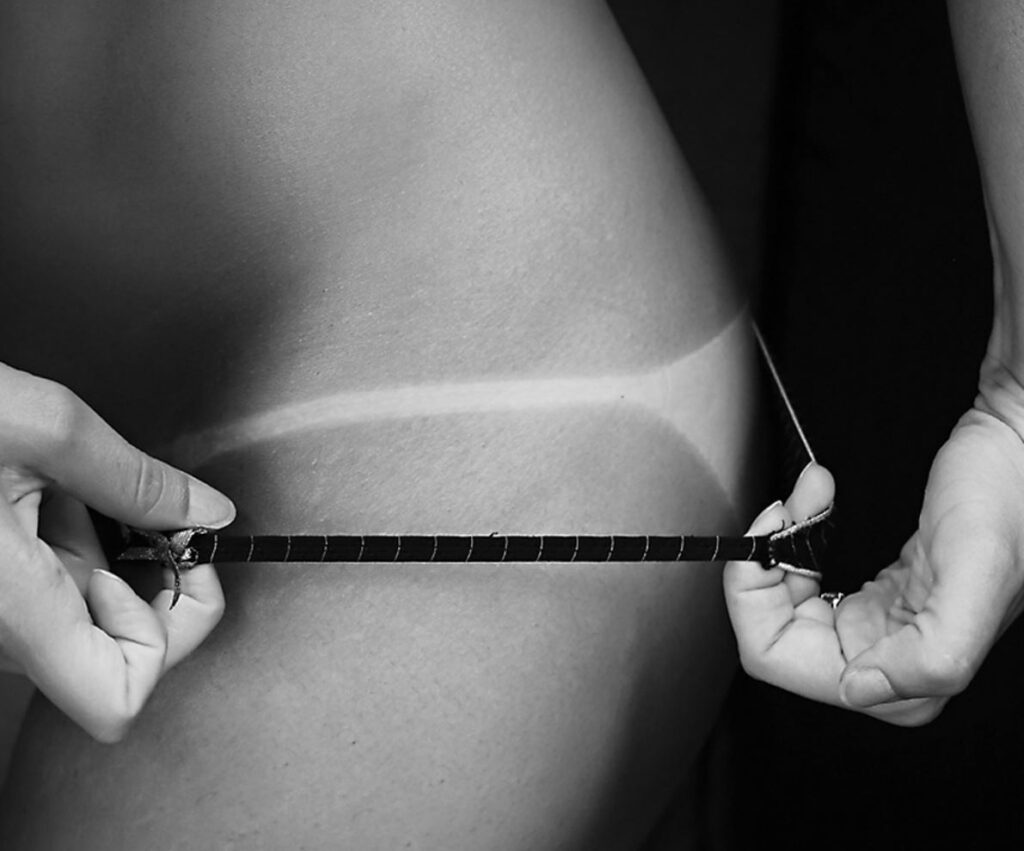Black and white close up of a tan line from a swimsuit.