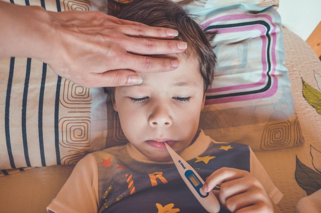 child in bed with a thermometer