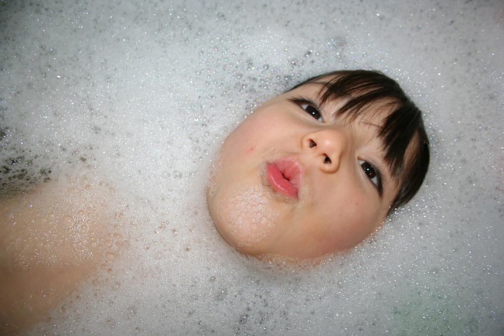 child in bath holding their head at water level