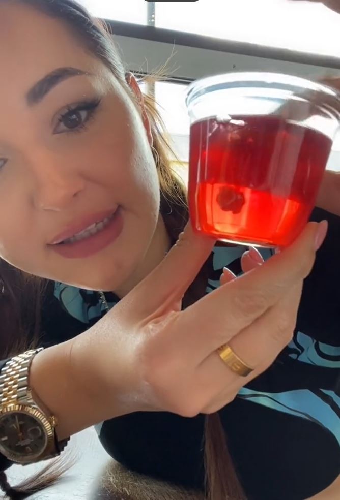 A woman holding a red Jello cup. Windows in the background. 