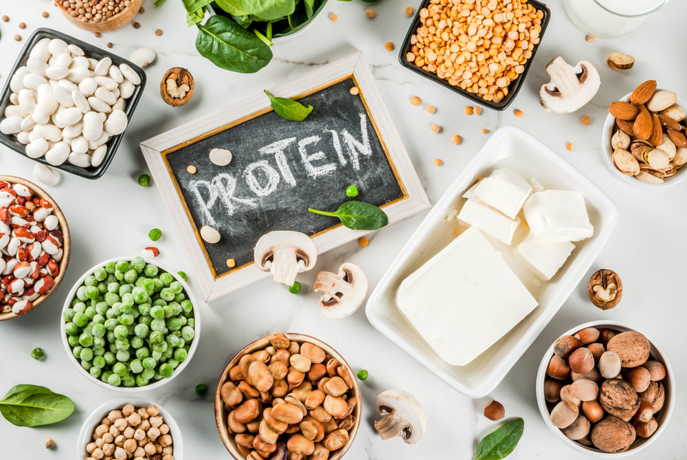 Healthy diet vegan food, veggie protein sources: Tofu, vegan milk, beans, lentils, nuts, soy milk, spinach and seeds. Top view on white table.
