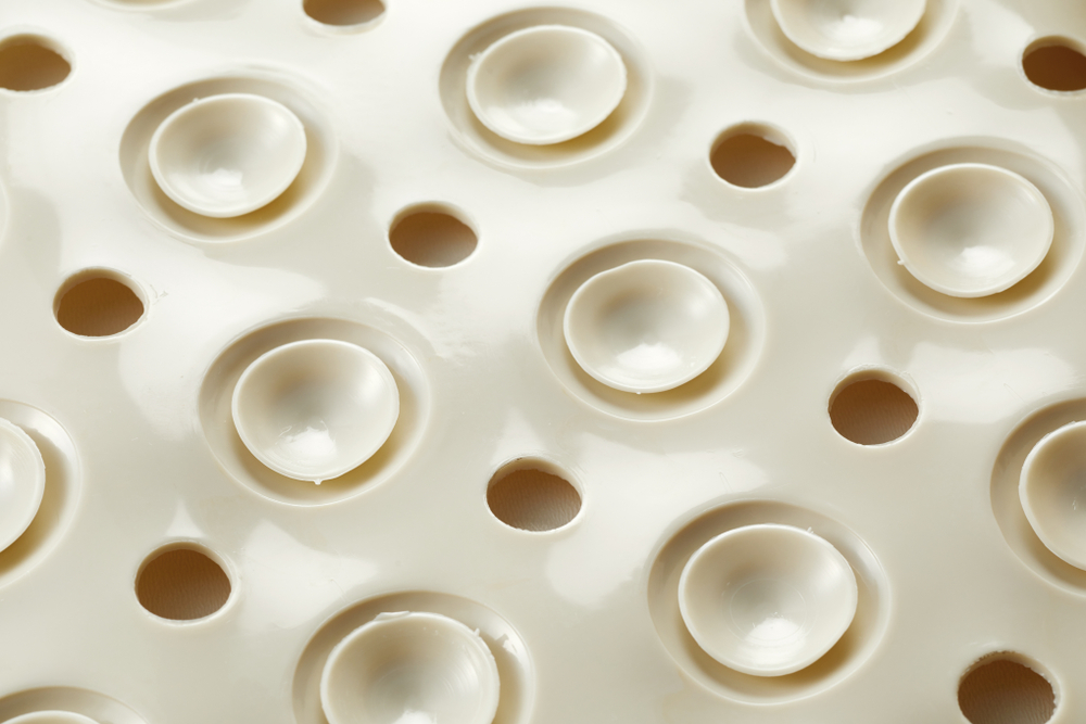 Underside of a rubber bath mat with suction pads to prevent slipping on a wet surface when bathing in a close up full frame view