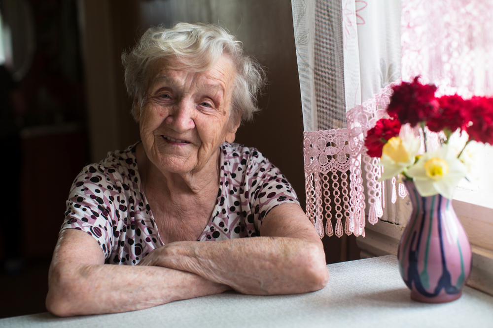 Elderly woman portrait near window in the house.