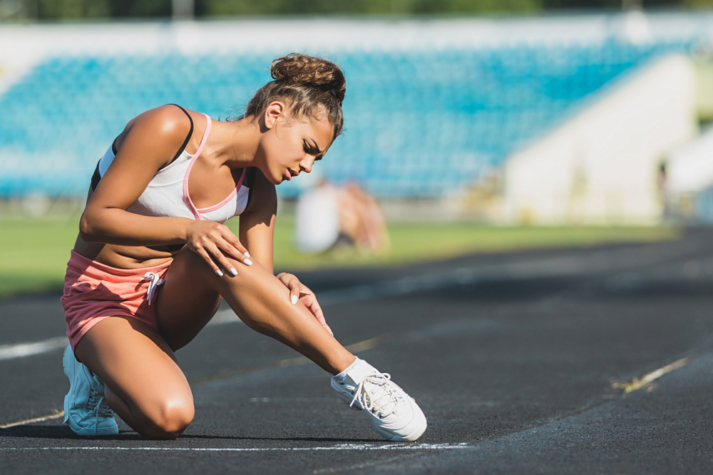 Runner suffering from leg cramp on the track