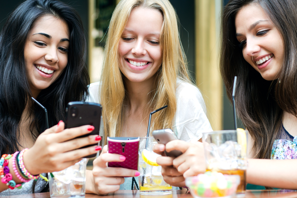 three girls chatting with their smartphones