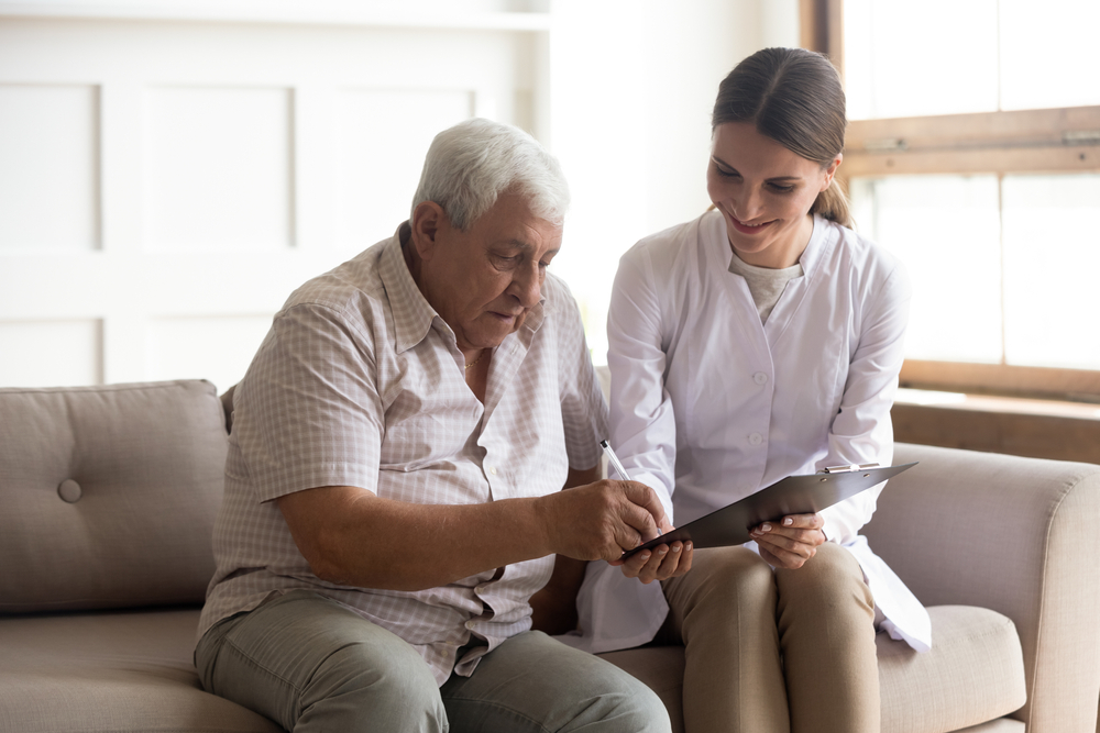 Smiling young female medical worker visit consult senior male patient sign health insurance contract, positive woman nurse or doctor close deal with mature man client, elderly healthcare concept