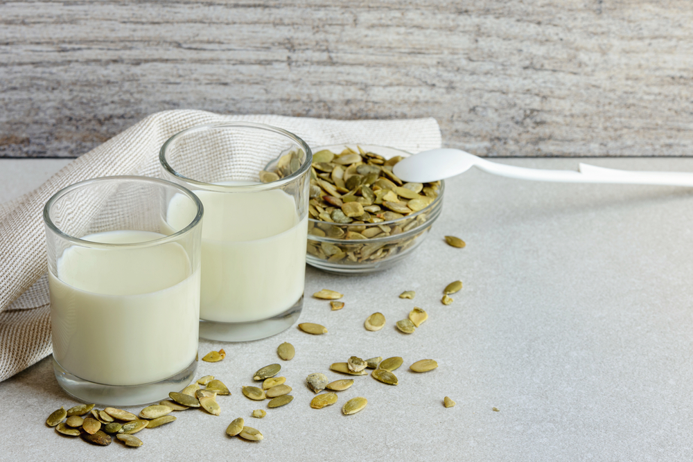 Close up homemade pumpkin seeds milk in small drinking glass with ingridients