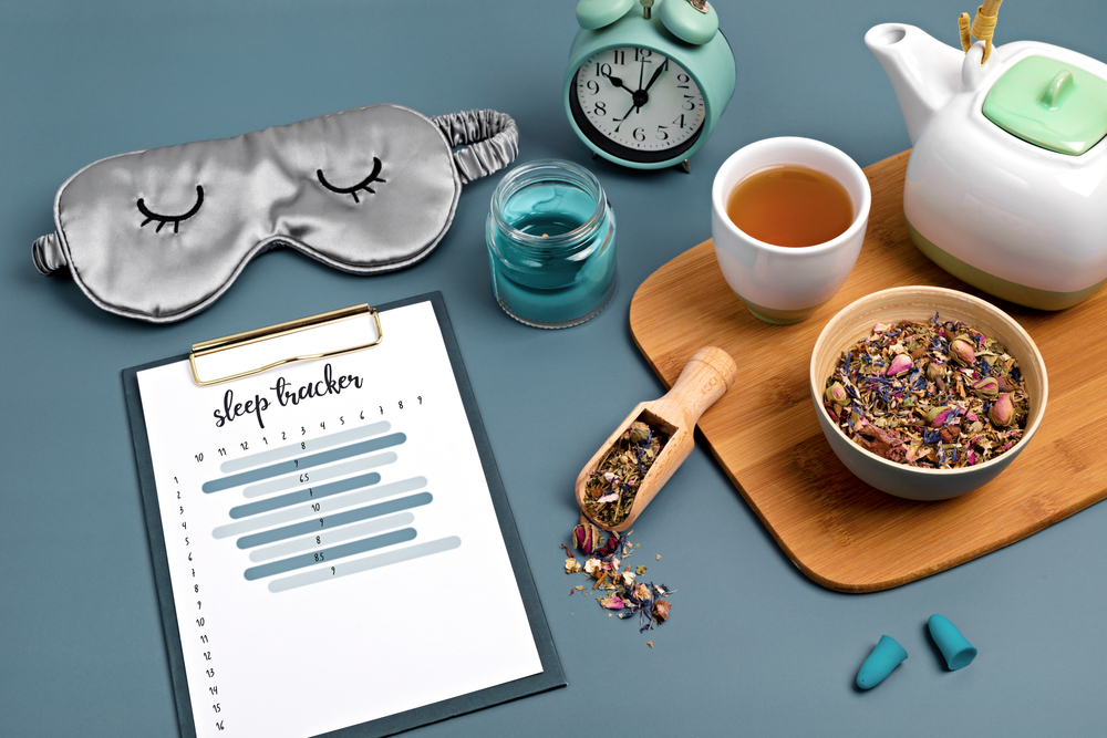 Classic alarm clock, sleeping mask, sleep tracker and herbal tea on blue background. Minimal concept of rest, quality of sleep, good night, insomnia, relaxation. Copy space