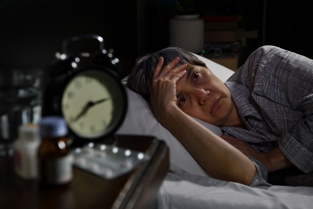 Depressed senior woman lying in bed cannot sleep from insomnia