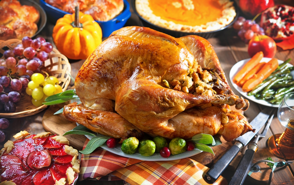 Thanksgiving turkey dinner. Roasted turkey on holiday table with pumpkins, pie, fruits, flowers and wine