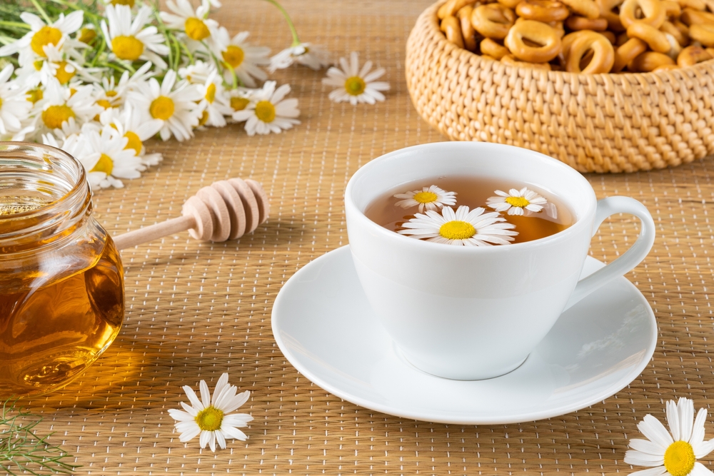 Herbal tea, chamomile flowers and honey on rattan matting Close-up
