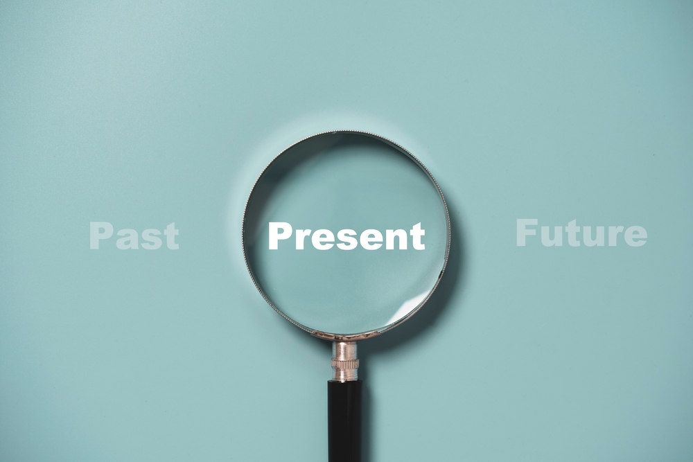 Present wording inside of Magnifier glass on blue background for focus current situation , positive thinking mindset concept.