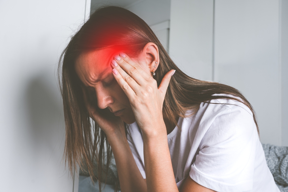 Young woman touching her temples and suffering from head pain, headache or migraine
